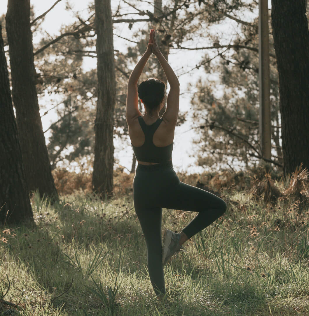 [NL]Frau beim Yoga in der Baum-Pose im Wald, achtsam und naturverbunden.