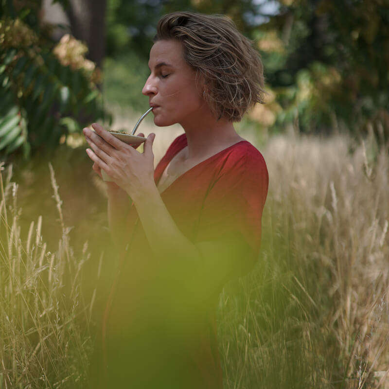 Frau trinkt Mate Tee aus Cuia im Feld